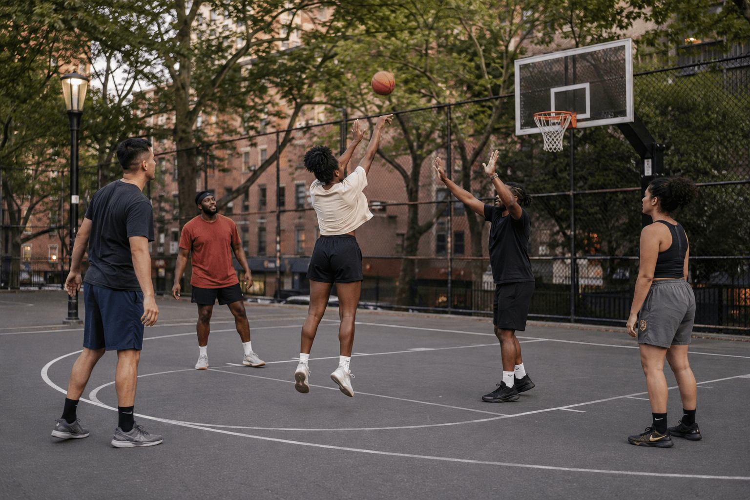 A woman takes a jump shot during a basketball game on an outdoor urban court.